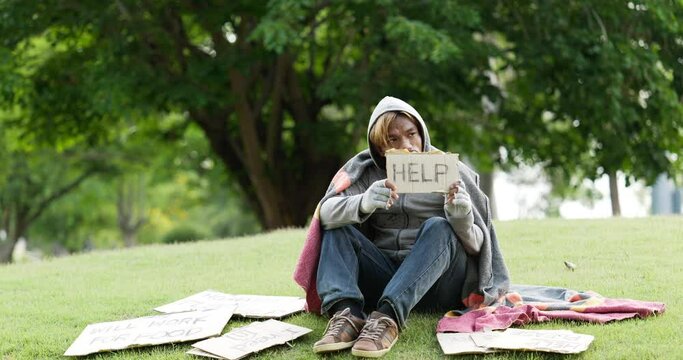 Homeless man sitting and holding help sign