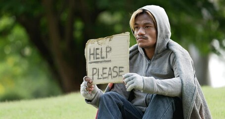 Homeless man sitting and holding help please sign