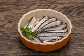 Anchovies in the bowl served basil leaves