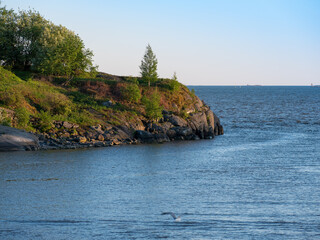 Fototapeta premium A beautiful view of a rocky skerry against blue sea during the sunset.