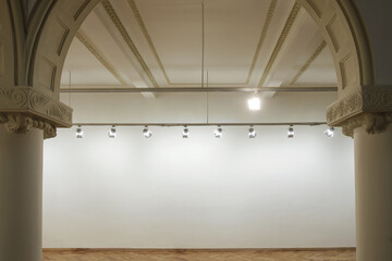 Interior of a empty white wall with spot lights at art gallery - obrazy, fototapety, plakaty