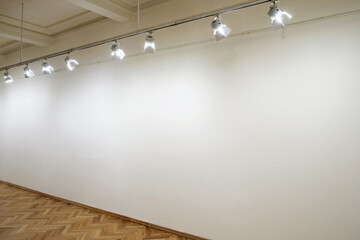 Interior with empty white wall in perspective with spot lights at art gallery