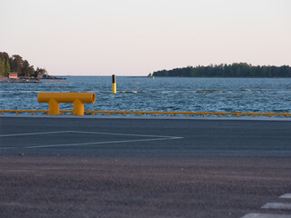 A beautiful sunset view of a horizon with two islands. A large yellow bollard in the foreground.