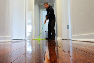 Man mopping a wooden floor at home corridor