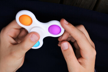 Hands of a child playing with pop it fidget spinner toy - obrazy, fototapety, plakaty