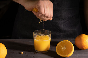 a man in a dark apron crushes orange juice