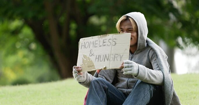 Homeless man sitting and holding homeless and hungry sign