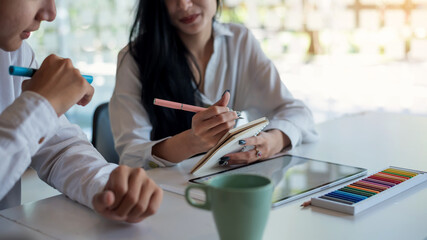 Image of the designers team working on a work idea by taking notes drawing on the tablet sampling paint at the office.