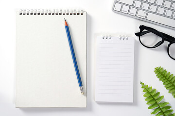 White Office Desk with Computer Notepad pencil Green leaf and other Supplies. Blank Paper sheet on right for input the text., Top View, Flat Lay.