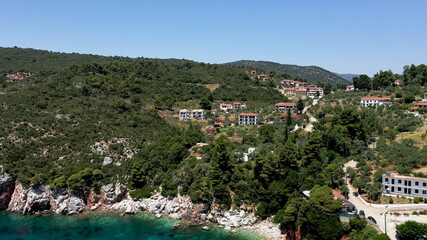 Fototapeta na wymiar Aerial drone views over a rocky coastline, crystal clear Aegean sea waters, touristic beaches and lots of greenery in Skopelos island, Greece. A typical view of many similar Greek islands.
