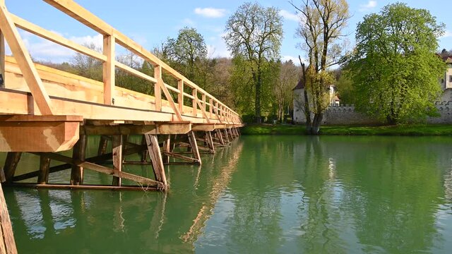 Famous landmark Otocec castle in Slovenia. New wooden bridge over the river Krka. Low angle view of beautiful landscape. Static shot, real time, wide angle