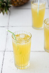 Delicious sweet refreshing pineapple juice with ice in glasses with a straw