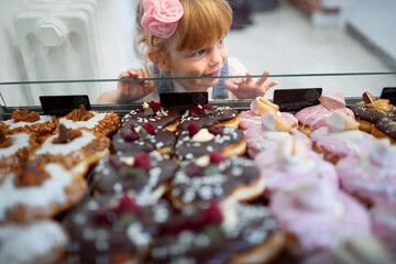 Portrait of a toddler girl picking up yummy donuts