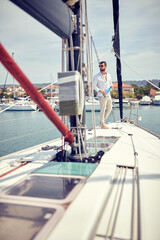 Fototapeta na wymiar A young man is enjoying a beautiful scenery of the town while riding on a yacht in the dock on the seaside. Summer, sea, vacation