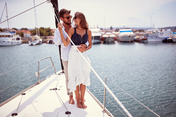 A young couple in love is standing in a hug on a yacht and spending romantic moments while riding...