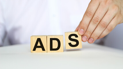 A businessman holds wooden cubes with a word ADSon a white background, with space to copy the text, business concept