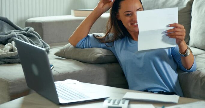 Happy young 30s girl reading paper letter, excited by good news. Overjoyed happy female student received university admission notification or grant payment.