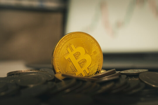 Bitcoins and virtual money concept. Gold bitcoins on a stack of coins with chart of growing and falling valuance of a cryptocurrency. Mining or blockchain technology.