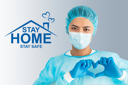 Doctor wear face mask, gloves, blue green uniform showing heart hands shape and stay home concepts - Powered by Adobe