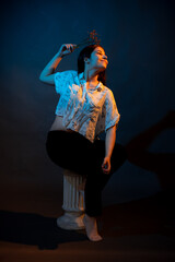 Girl on a stand on a dark background with multicolored light