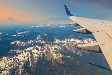 Flying over snow capped mountains, view of airplane wing, Seattle