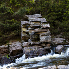 Stone foundation of old mill with streaming water and forest background. Shot in Sweden, Scandinavia