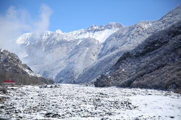 Winter and mountains . There is fog at the foot of the mountains . It snowed on the river stones. In winter, the river water decreased