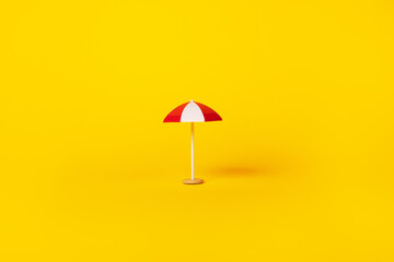 red and white beach umbrella over yellow background, summertime and vacation concept