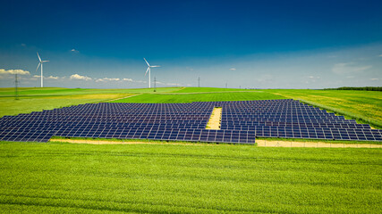 Solar panels, wind turbines on green field. Alternative energy, Poland.