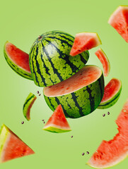 Ripe and juicy watermelon falling in the air isolated on a pastel green background. Creative food...