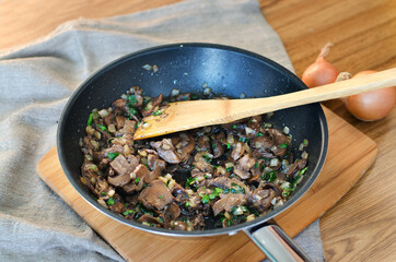 Cooked mushrooms in frying pan on wooden table, close up view.