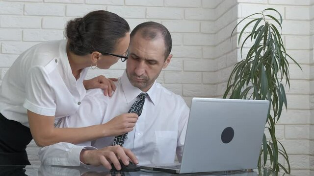 A man is sexually harassed. The female boss touches the male subordinate by the tie.