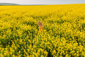 Obraz premium Aerial view of woman at blooming rapeseed field. Yellow flowers and happy young woman