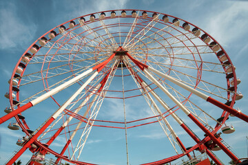 A large red and white Ferris Wheel against a blue sky