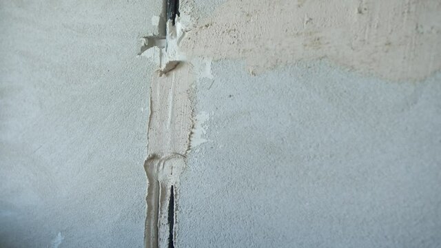 Unrecognizable man plastering concrete wall with wire