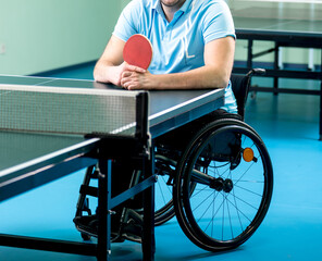 Adult disabled man in a wheelchair training before play at table tennis