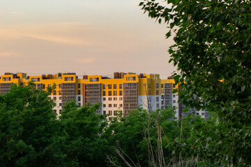 Naklejka premium Volgograd / Russia - May 2021: bright new building, high-rise building framed by green foliage of trees