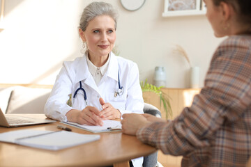 Middle aged female doctor therapist in consultation with patient in office.