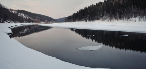The last rays of the setting sun over an ice-covered river in the Urals in winter