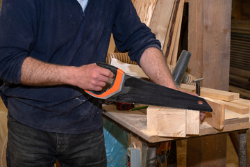 Production of custom-made wooden furniture. A master carpenter cuts a wooden workpiece with a saw. Woodworking. Selective Focus