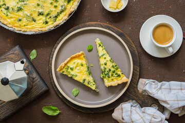 Sliced quiche pie with spinach, green peas, asparagus beans and egg topping on a ceramic plate on a...
