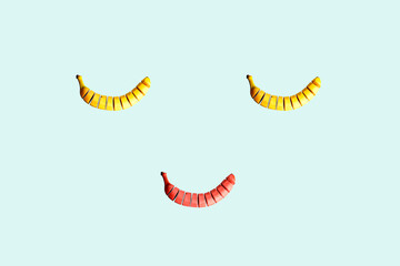 Smiling face concept made of bananas isolated on bright blue background