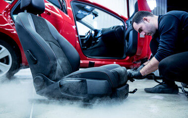 Fototapeta premium Car service worker cleaning car seat with a steam cleaner