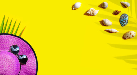 Summer hat with exotic seashells on yellow background.