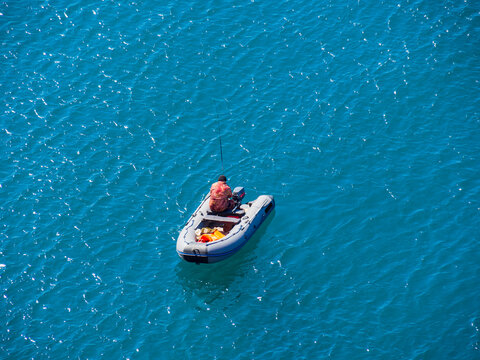 A Lone Boat With Industrial Fishermen In The Open Sea With A Rod And Nets. The Concept Of Poaching And Illegal Fishing.