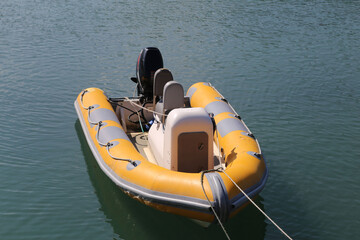 A bright yellow inflatable dinghy with outboard motor moored by the quayside in Fishguard,...