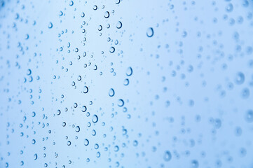 Close-up of raindrops or snow drops on a blue windowpane. Freshness background and texture of drops on the surface