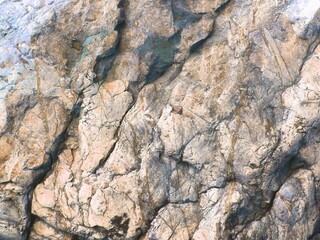 Natural rock formation wall layers stone background texture of mountain cliff .Textured grunge marble cracks vein structure photo wallpaper design.Marbled Grey blue brown yellow white colors.