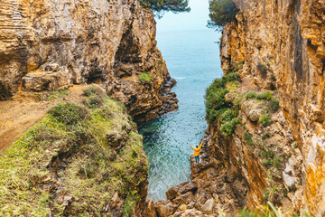 Obraz premium man in yellow raincoat hiking to sea beach at canyon
