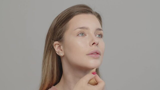 Makeup artist or stylist applies foundation using wet sponge to the face of the female model. Visagiste  applying cosmetic concealer base on a face. Professional makeup. Tutorial makeup master class
